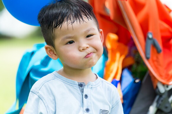 Sweaty Asian toddler smirks during extreme heat in the Philippines.